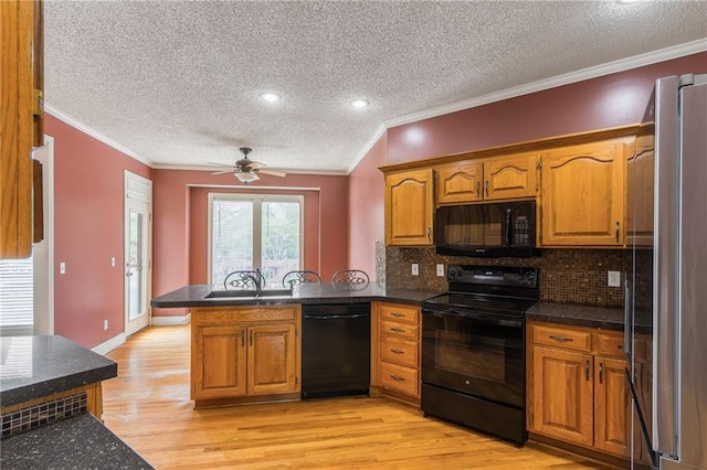 7428 N Smalley Ave, Kansas City, MO 64158 - kitchen featuring black appliances, a peninsula, a textured ceiling, ornamental molding, and light wood-style flooring