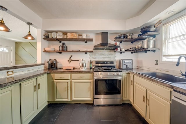 kitchen featuring wall chimney range hood, appliances with stainless steel finishes, open shelves, a sink, and cream cabinetry