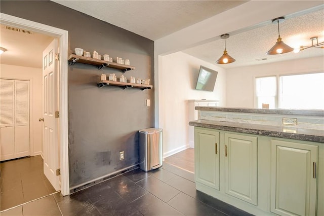 kitchen featuring dark tile patterned flooring, pendant lighting, stone countertops, baseboards, and green cabinets