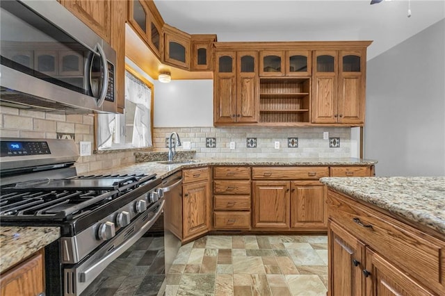 316 W 5th Ave, Garnett, KS 66032 - kitchen with stainless steel appliances, a sink, brown cabinetry, and stone finish flooring