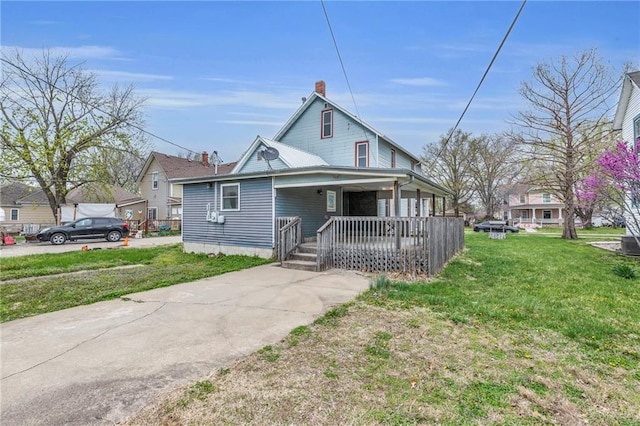 316 W 5th Ave, Garnett, KS 66032 - view of front facade with covered porch, a chimney, a front yard, and concrete driveway