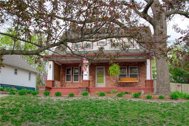 view of front of home with brick siding, a porch, and a front yard
