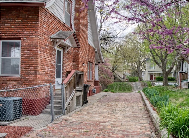 view of home's exterior featuring fence, brick siding, and central AC unit