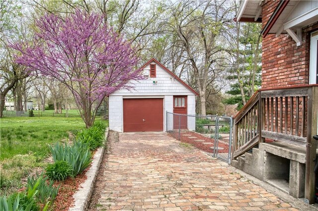 detached garage with fence and decorative driveway