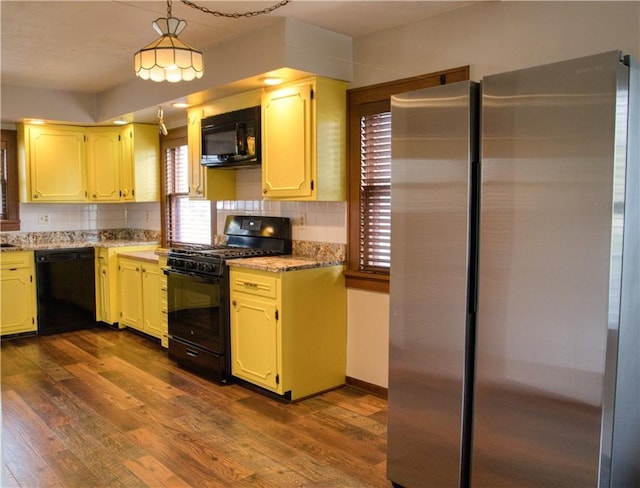 kitchen with dark wood finished floors, backsplash, light stone counters, decorative light fixtures, and black appliances
