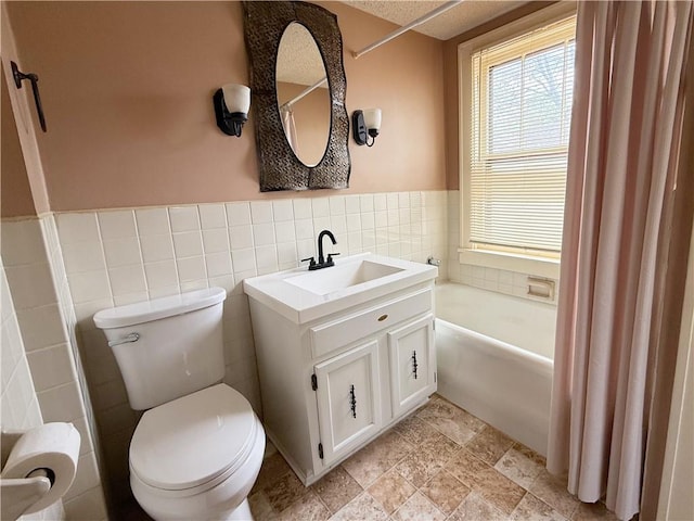 full bathroom featuring toilet, a healthy amount of sunlight, a bathing tub, and tile walls