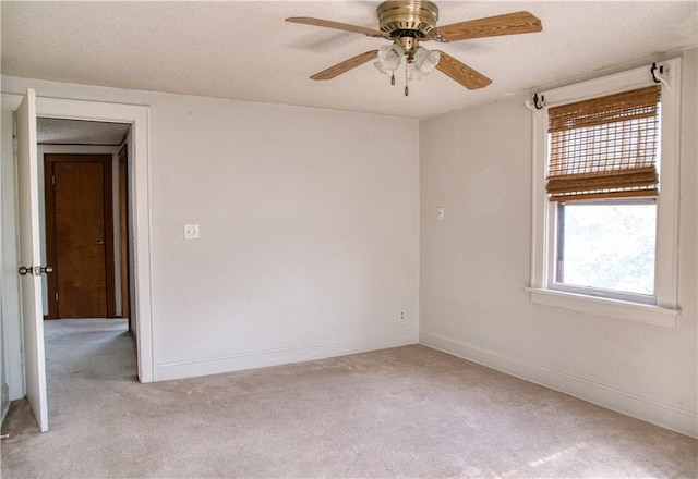 unfurnished room featuring a ceiling fan, baseboards, a textured ceiling, and light colored carpet
