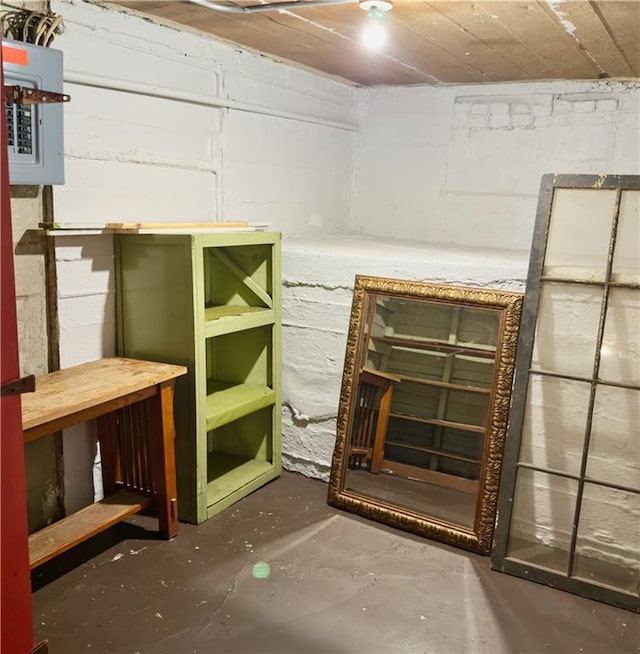 unfinished basement featuring concrete block wall and electric panel