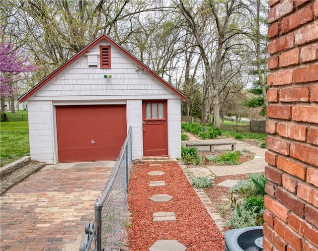 detached garage featuring central air condition unit, fence, and decorative driveway