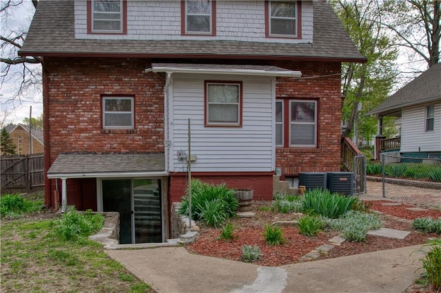 view of front of property with fence, a shingled roof, and central air condition unit