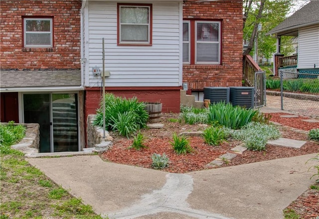 exterior space with fence, brick siding, and cooling unit