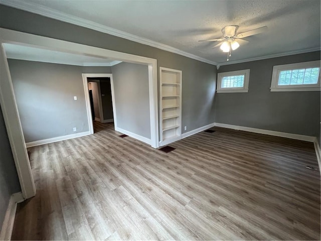 5702 Euclid Ave, Kansas City, MO 64130 - empty room featuring crown molding, wood finished floors, built in shelves, ceiling fan, and baseboards