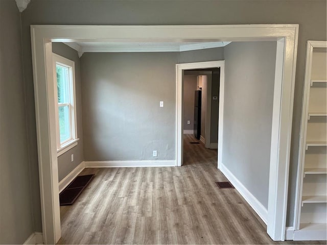 5702 Euclid Ave, Kansas City, MO 64130 - spare room with baseboards, crown molding, wood finished floors, and visible vents