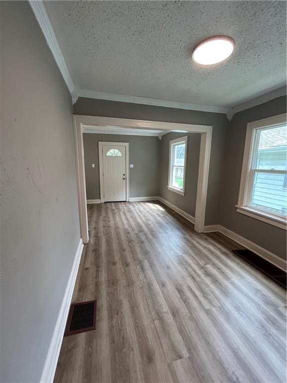 5702 Euclid Ave, Kansas City, MO 64130 - interior space with wood finished floors, visible vents, ornamental molding, baseboards, and a textured ceiling