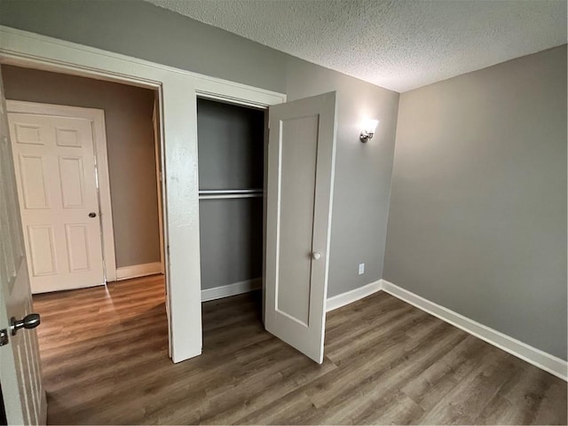 5702 Euclid Ave, Kansas City, MO 64130 - unfurnished bedroom with baseboards, wood finished floors, a textured ceiling, and a closet