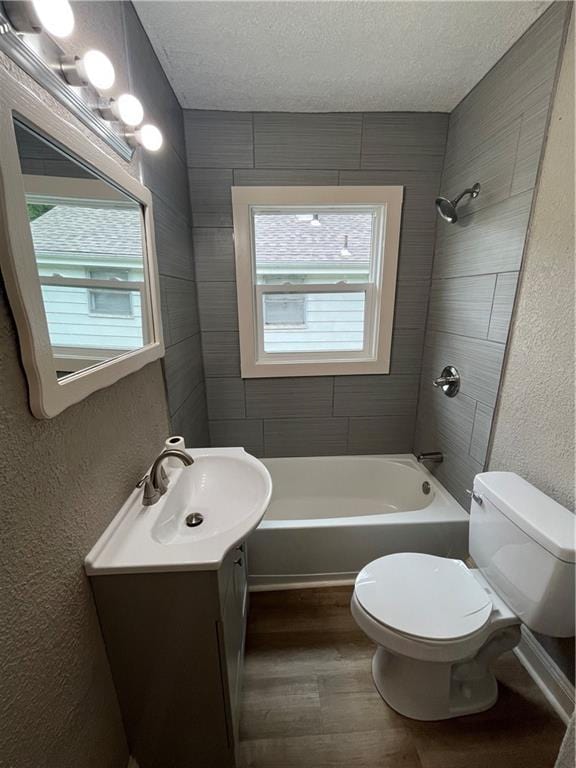 5702 Euclid Ave, Kansas City, MO 64130 - bathroom with wood finished floors, toilet, vanity, shower / tub combination, and a textured ceiling