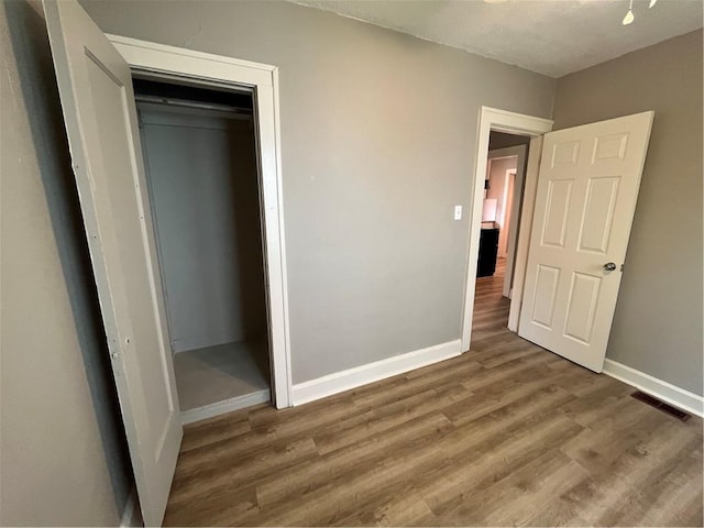 5702 Euclid Ave, Kansas City, MO 64130 - unfurnished bedroom with baseboards, wood finished floors, visible vents, and a closet