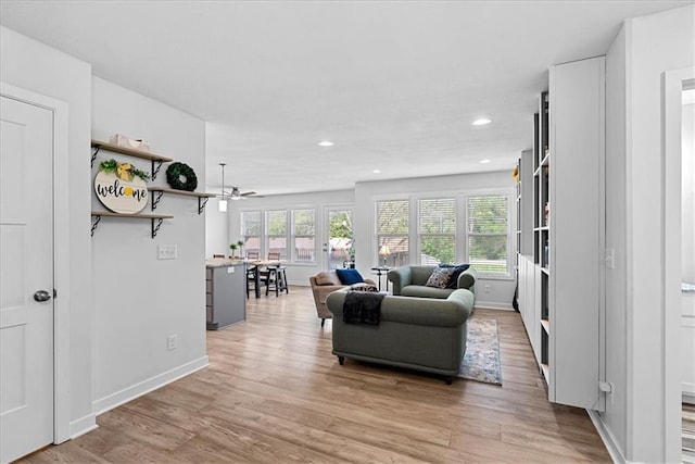 living area featuring baseboards, ceiling fan, recessed lighting, and light wood-style flooring
