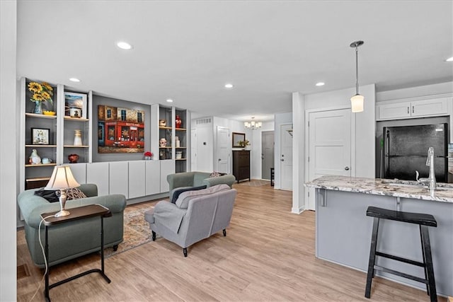 living area with light wood-type flooring, recessed lighting, and a chandelier