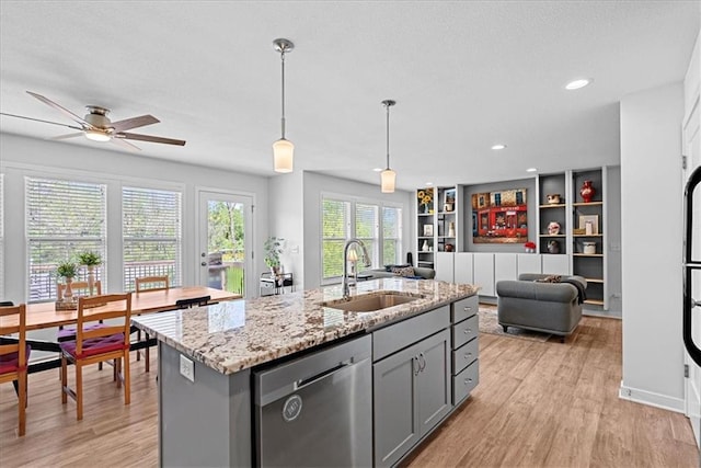 kitchen featuring stainless steel dishwasher, gray cabinetry, a sink, and light wood-style flooring