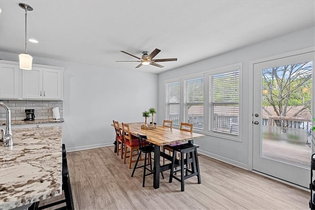 dining space with plenty of natural light, a ceiling fan, light wood-style floors, and baseboards