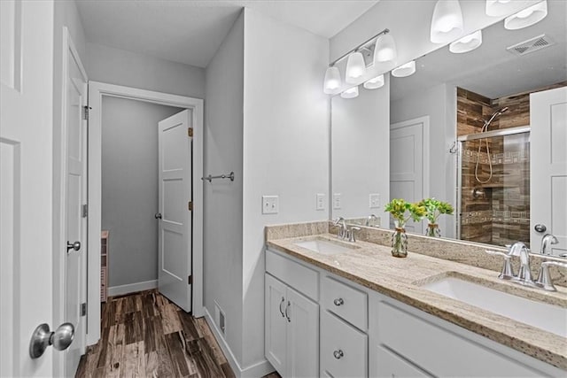 full bathroom with a sink, a shower stall, wood finished floors, and visible vents