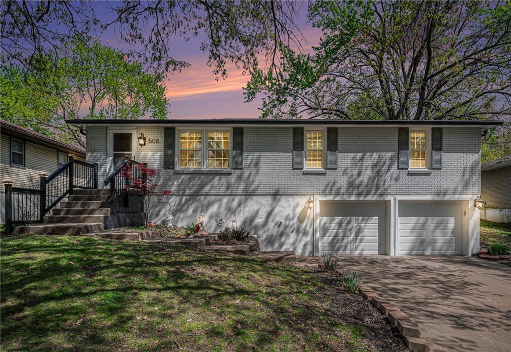 508 NW 88th St, Kansas City, MO 64155 - ranch-style house with an attached garage, driveway, brick siding, and a yard