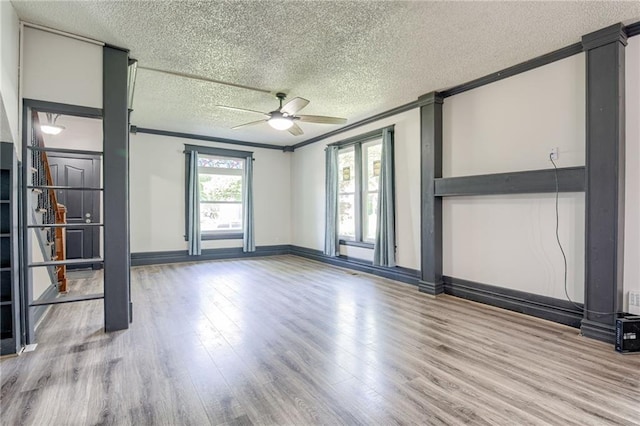 spare room with a textured ceiling, ceiling fan, wood finished floors, crown molding, and baseboards