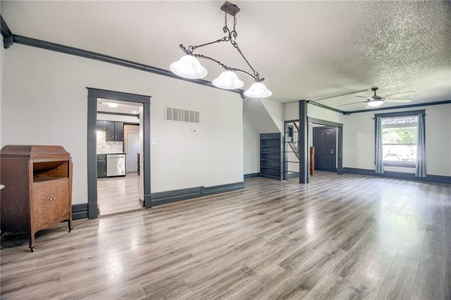 unfurnished living room featuring a textured ceiling, a ceiling fan, wood finished floors, crown molding, and baseboards