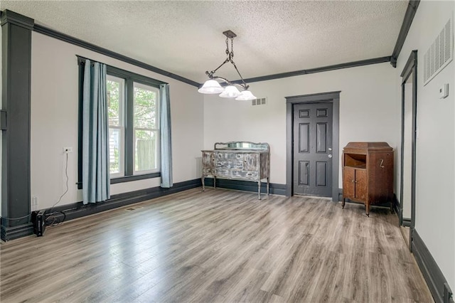 dining room with crown molding, a textured ceiling, light wood-style flooring, and baseboards