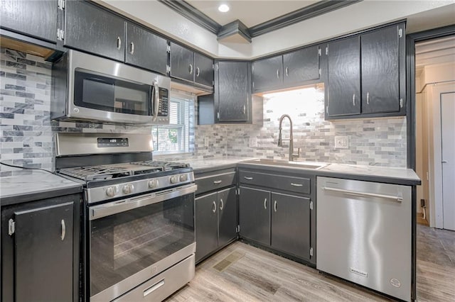 kitchen featuring appliances with stainless steel finishes, a sink, crown molding, backsplash, and recessed lighting
