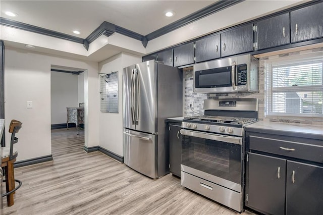 kitchen with appliances with stainless steel finishes, crown molding, light wood finished floors, tasteful backsplash, and baseboards