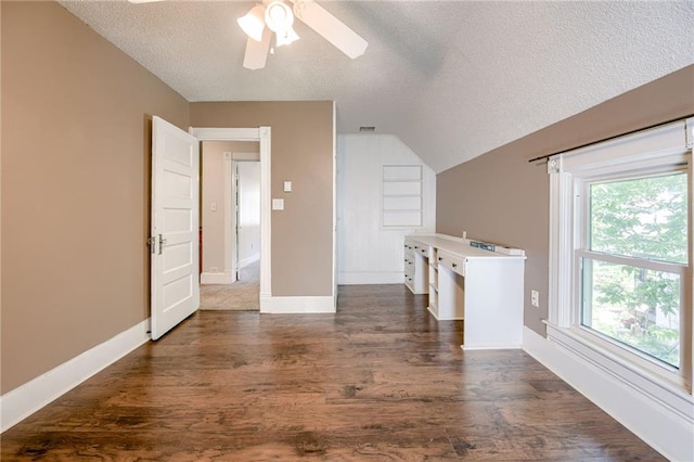 bonus room featuring a textured ceiling, dark wood-type flooring, a ceiling fan, baseboards, and vaulted ceiling