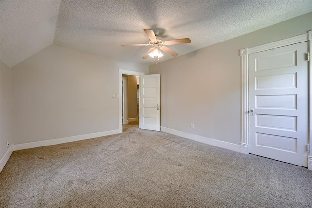 unfurnished bedroom featuring carpet flooring, a textured ceiling, baseboards, a ceiling fan, and lofted ceiling
