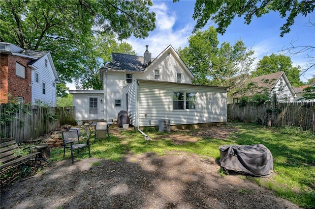 back of house featuring a chimney and central AC unit