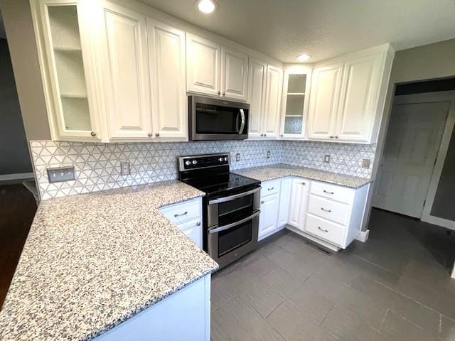 3106 Mill Ct, Pittsburg, KS 66762 - kitchen featuring stainless steel appliances, light stone countertops, white cabinets, decorative backsplash, and glass insert cabinets