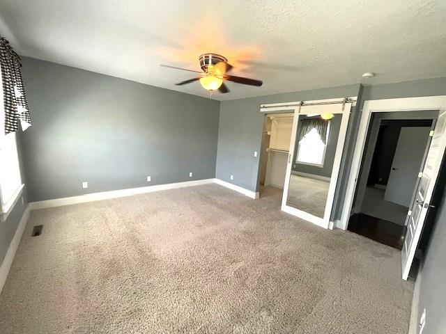 3106 Mill Ct, Pittsburg, KS 66762 - unfurnished bedroom featuring baseboards, light colored carpet, a ceiling fan, a spacious closet, and a closet