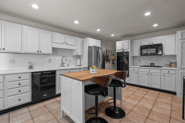 1215 W 69th Ter, Kansas City, MO 64113 - kitchen featuring black appliances, recessed lighting, a kitchen breakfast bar, white cabinets, and light tile patterned floors