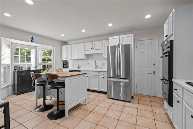 1215 W 69th Ter, Kansas City, MO 64113 - kitchen with freestanding refrigerator, wooden counters, white cabinetry, recessed lighting, and a center island