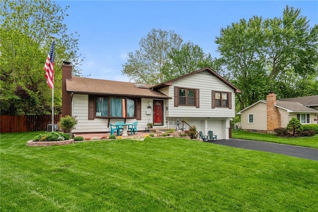 13613 Lowell Ave, Grandview, MO 64030 - split level home featuring an attached garage, driveway, a chimney, and central air condition unit