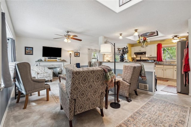 13613 Lowell Ave, Grandview, MO 64030 - living room featuring ceiling fan, a textured ceiling, light carpet, and a skylight