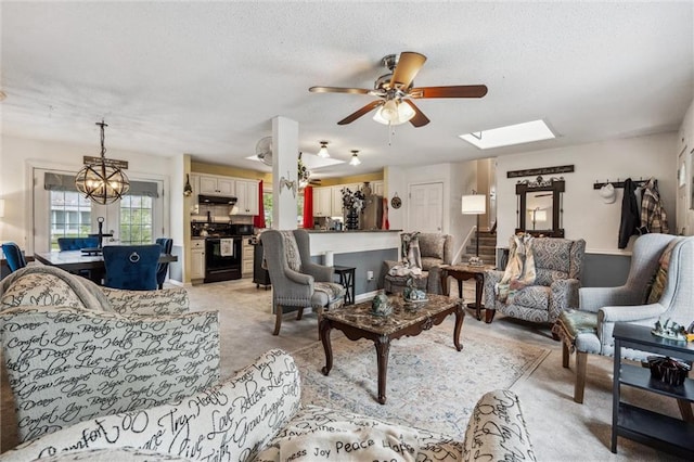 13613 Lowell Ave, Grandview, MO 64030 - living room featuring a textured ceiling, light carpet, a ceiling fan, a skylight, and a chandelier
