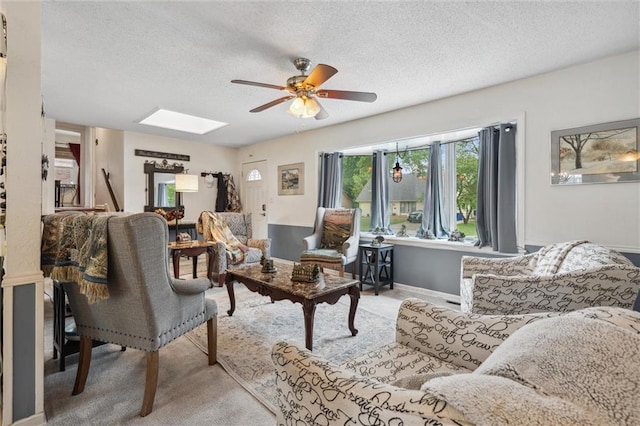 13613 Lowell Ave, Grandview, MO 64030 - living room featuring a ceiling fan, a skylight, a textured ceiling, light carpet, and baseboards