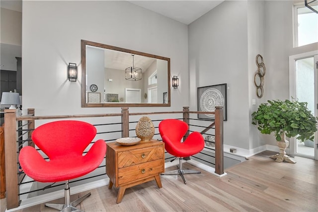 living area featuring baseboards, wood finished floors, an upstairs landing, and an inviting chandelier