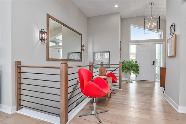 entrance foyer with baseboards, high vaulted ceiling, wood finished floors, and a chandelier