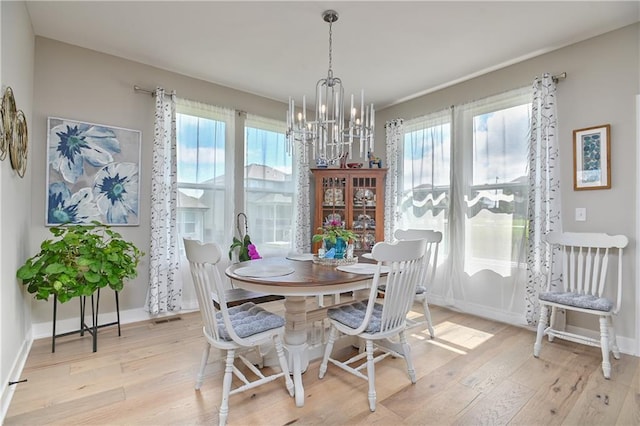 dining room featuring baseboards, visible vents, wood finished floors, and a notable chandelier