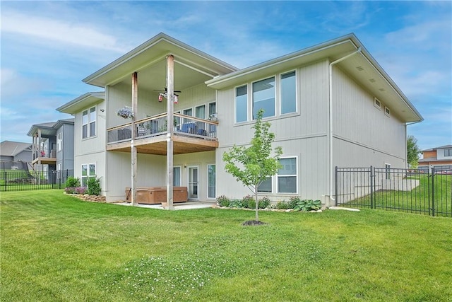 rear view of house featuring a hot tub, a lawn, a balcony, and a fenced backyard