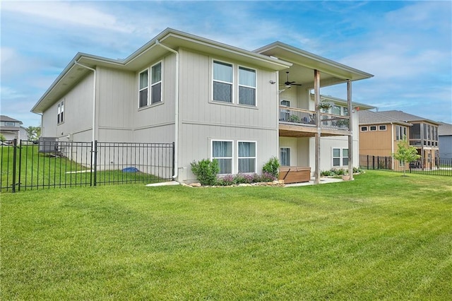 back of house with fence, a ceiling fan, a yard, and a balcony