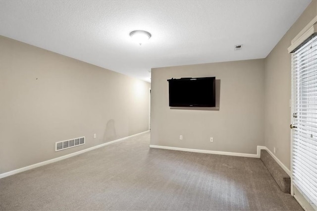 spare room featuring visible vents, a textured ceiling, carpet, and baseboards