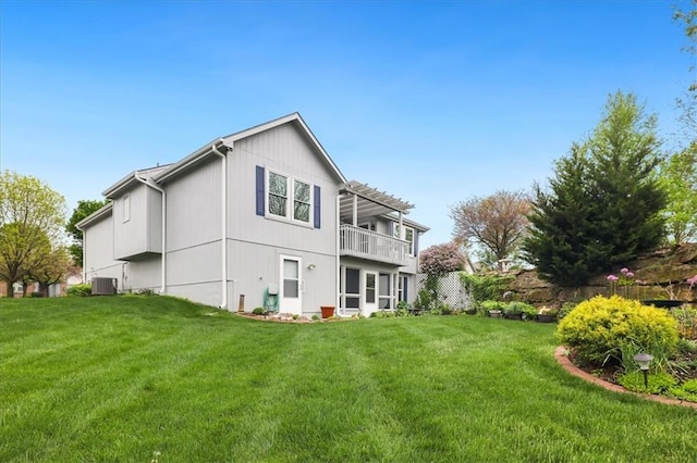 rear view of house featuring a yard, central AC, and a balcony